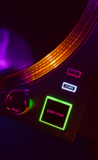 Gros plan sur un coin d'une platine vinyle avec quelques boutons en gros plan et en couleurs flashy.